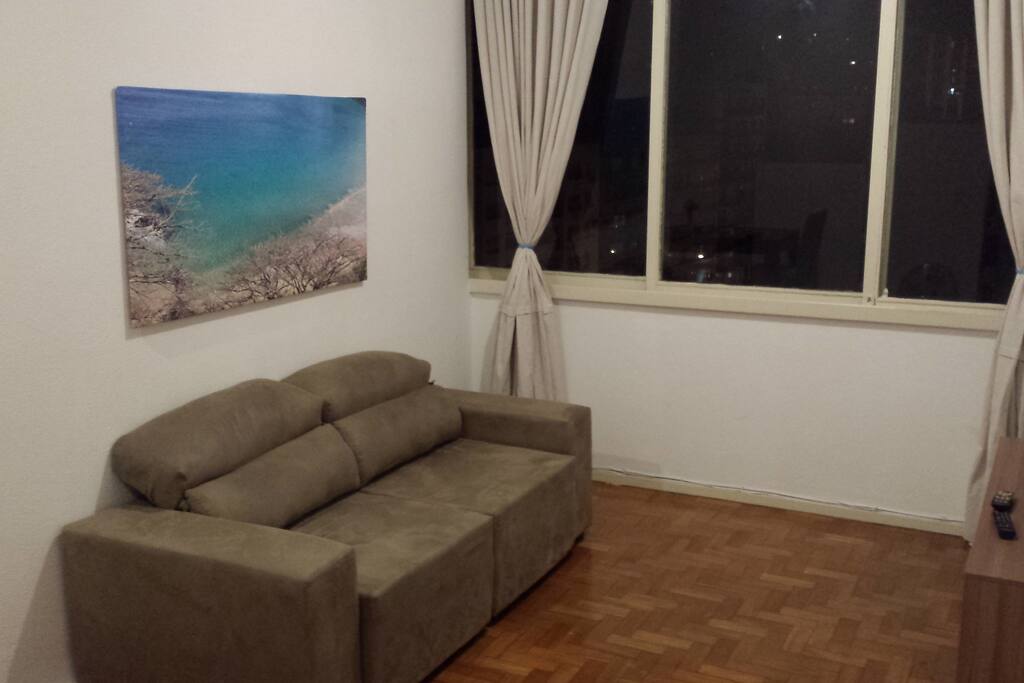 Sofá Retrátil 3 lugares. Sala Ampla com janelas grandes e pé direito alto de 3m 20cm.