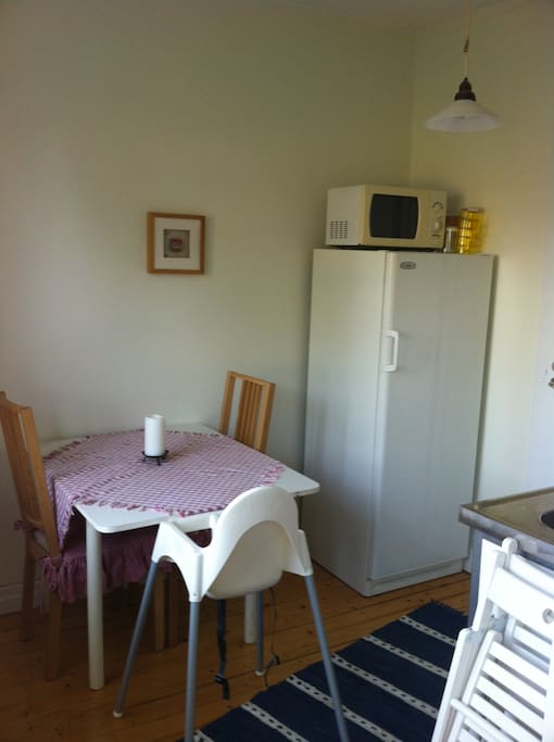 Kitchen with room for four. There is a fridge, microwave and a cooker.