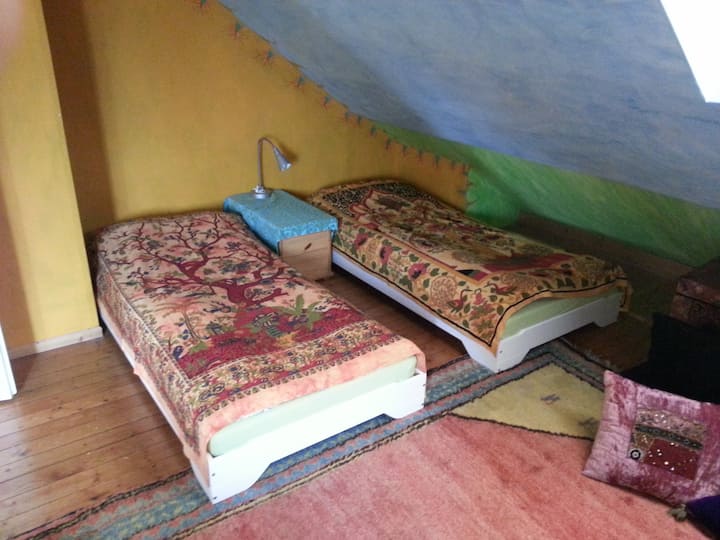 Habitación amarilla en el segundo piso con 2 camas individuales una junto a la otra.