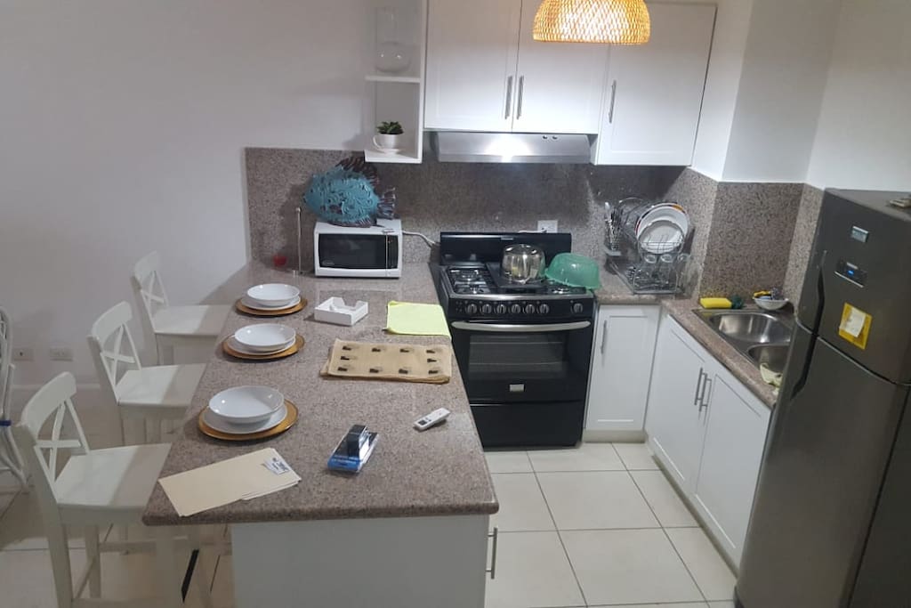 Cocina con accesorios: estufa, microondas, cafetera, nevera y demas utensilios. Kitchen with accessories: stove, microwave, coffee maker, refrigerator and other utensils.