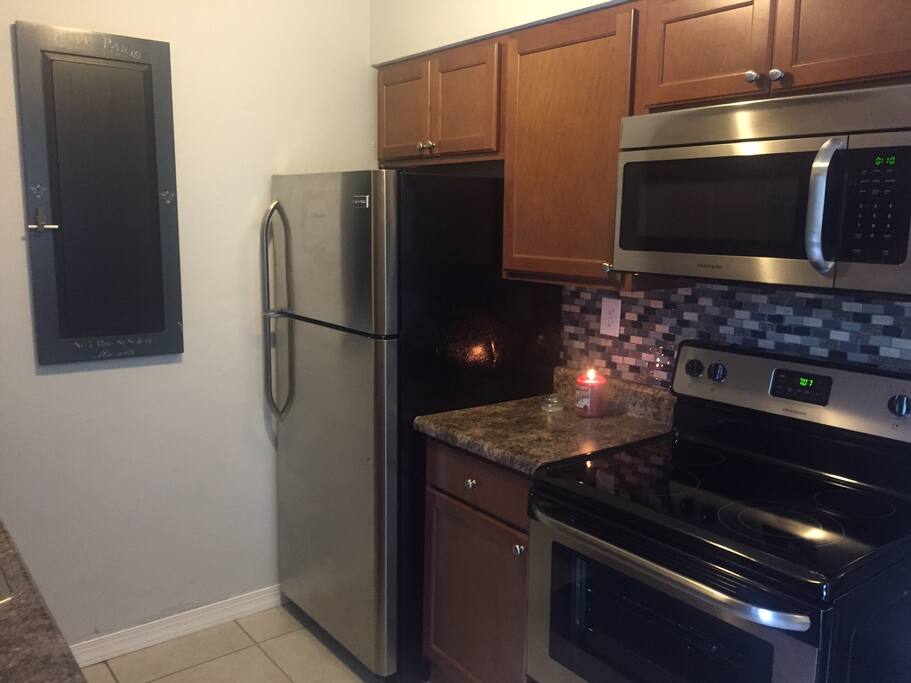 Newly renovated kitchen with stainless steel appliances, dishes, and silverware for cooking at home.