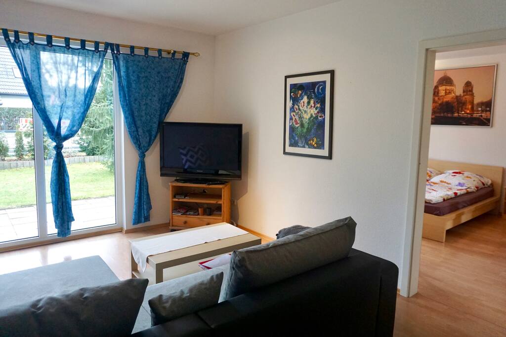 Wohnzimmer mit einer großen Fensterfront und einem Flachbildfernsehr