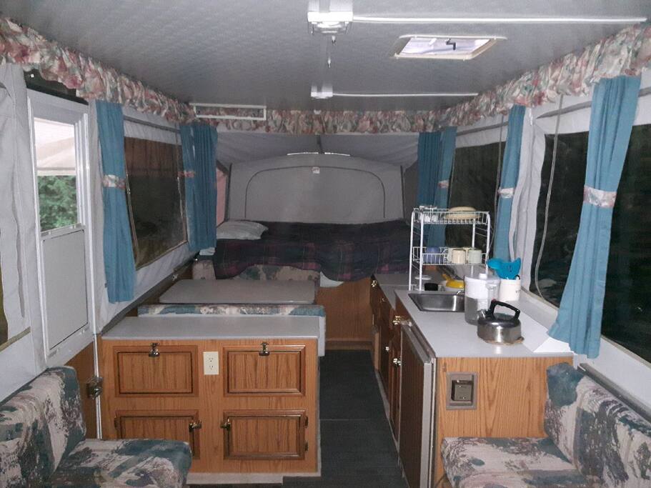 Inside has table and benches, sink and cabinets; queen bed in back.