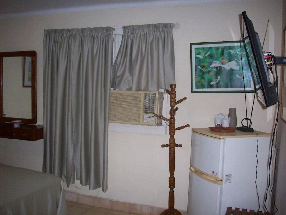 Bedroom # 1 with TV, air conditioner and small refrigerator.