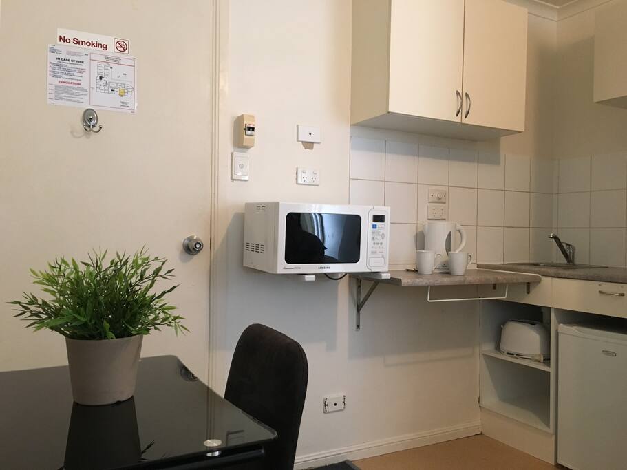 Twin room contains a kitchenette with cupboards, sink, microwave, fridge, kettle, toaster, cutlery and crockery