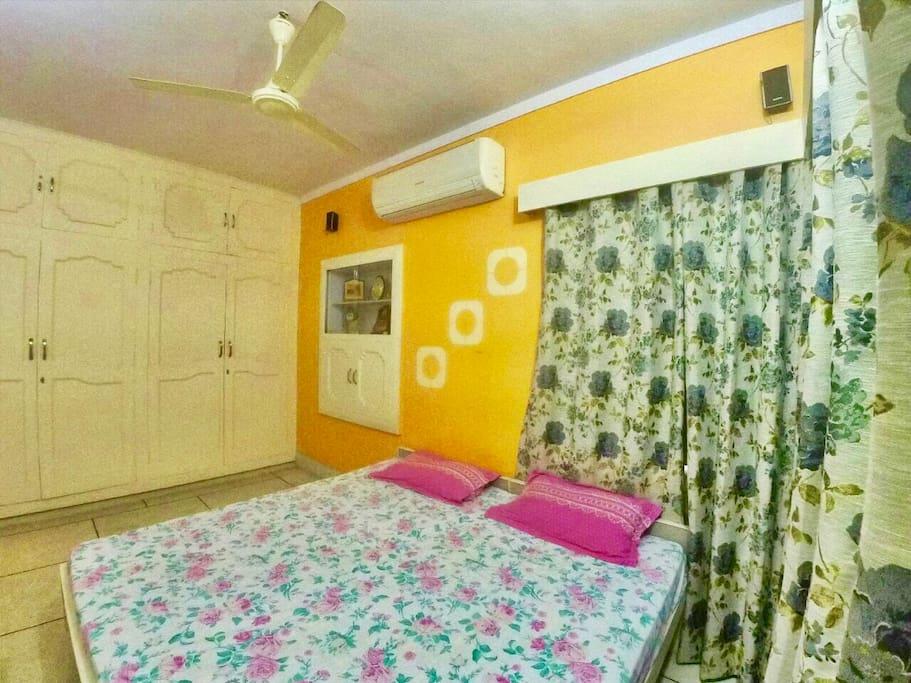 Room 1(AC): A calming Sun Orange colored room, comes with top notch O'General AC. It has a Wardrobe and a 5.1 Sony music system. This room is well lit with windows in two walls.