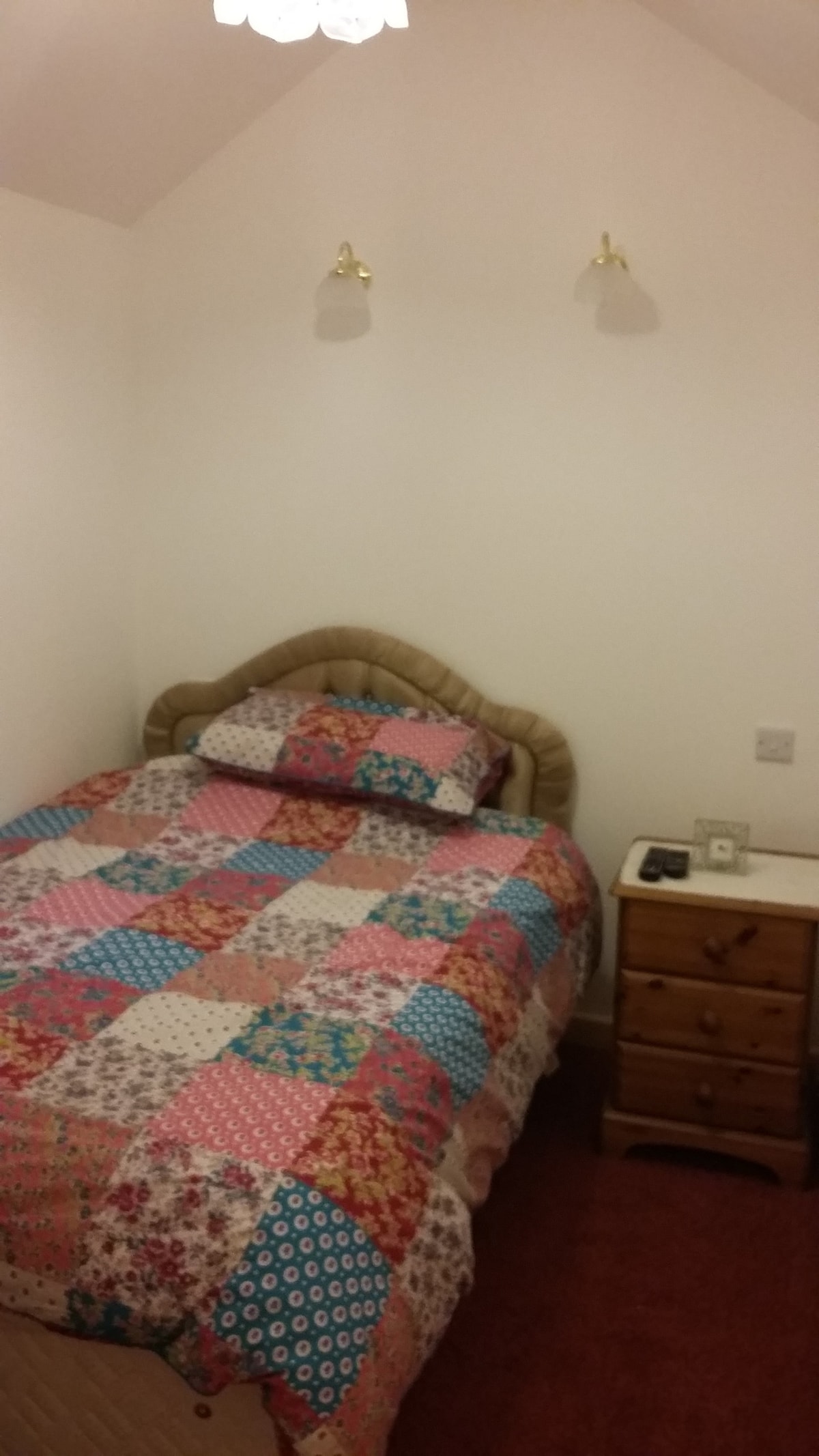 Cama doble pequeña en el tercer dormitorio con cajones, mesita de noche y espacio para colgar ropa.