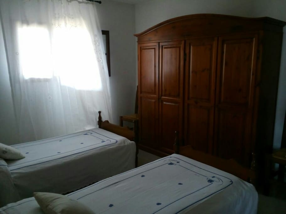 Small double bedroom with 2 single beds, wardrobe and couch.