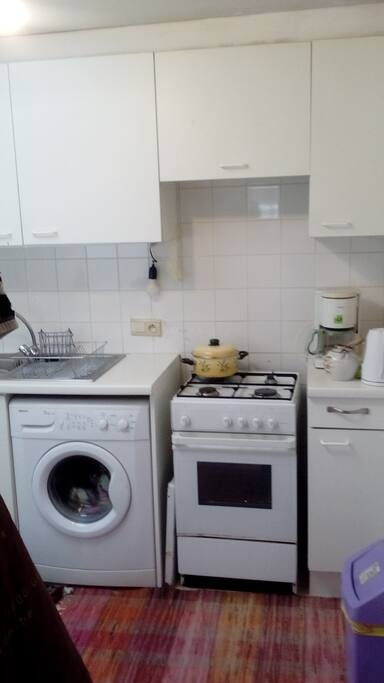 Kleine keuken mat gasfornuis, gasoven en wasmachine. Koffiezet en alle benodigdheden die nodig zijn om lekker te kunnen kokkerellen.