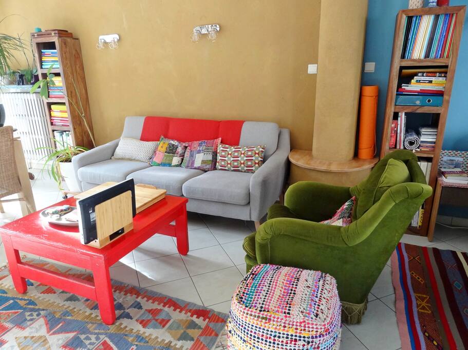Espace salon équipé : canapé, fauteuil, pouf, tapis de sol, table pliante pour ordinateur en bambou, repose tablette en bambou, tapis turque et table basse peinte à la main. Le canapé ne se déplie pas mais est confortable pour dormir.