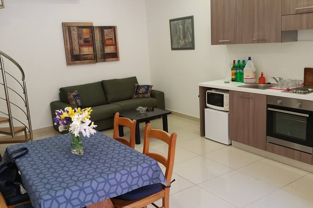 Living room with kitchen, dining and sitting spaces. Sofa converts to double bed.