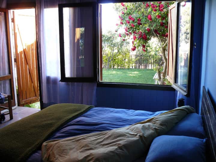 Голема спална соба со брачен кревет и поглед кон градината и морето