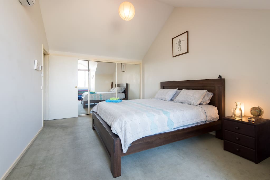 Top floor bedroom with comfortable, new king bed, new luxury bed linens, empty drawers and wardrobe space, mirrors, futon sofa, and a beautiful view over the Yarra Bend parkland