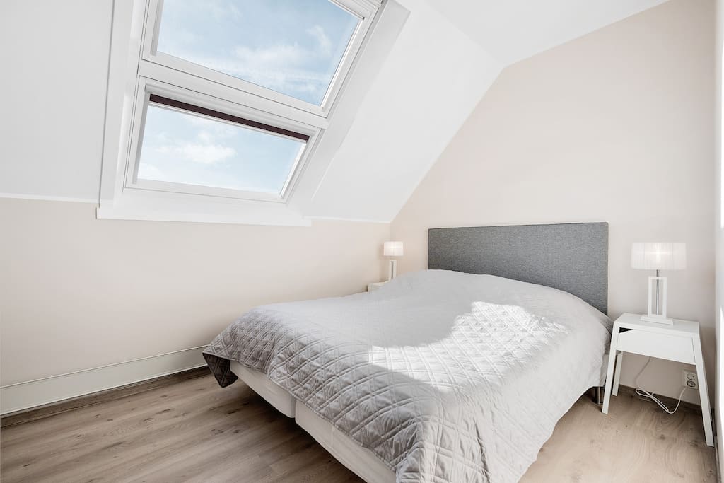 Bedroom no. 1, with a queen sized bed, lots of natural light, sun blocking shades, closet space and a writing desk.