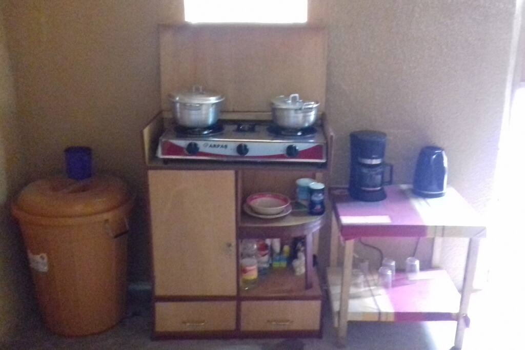 coin cuisine avec plaque de cuisson au gaz, cafetière, bouilloire, et vaisselle