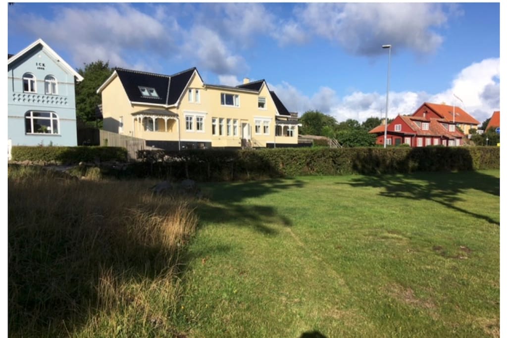 Huset set fra det grønne område, som ligger mellem huset og havet. Lejligheden er den midterste i stueetagen.