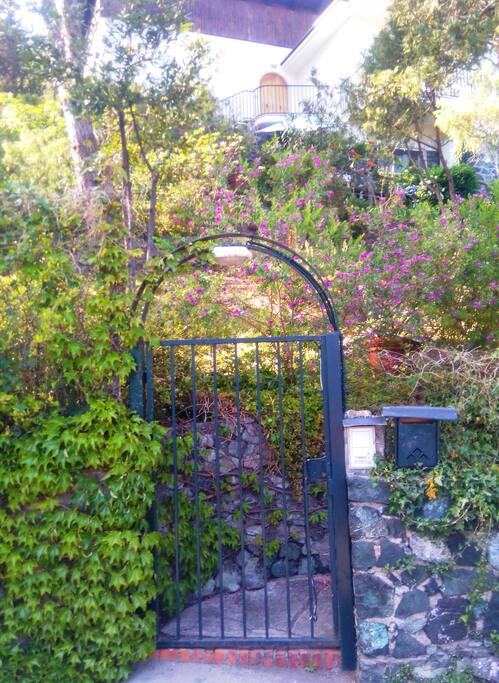 Accès au jardin depuis le chemin d'accès privé et porte d'entrée de la villa en second plan