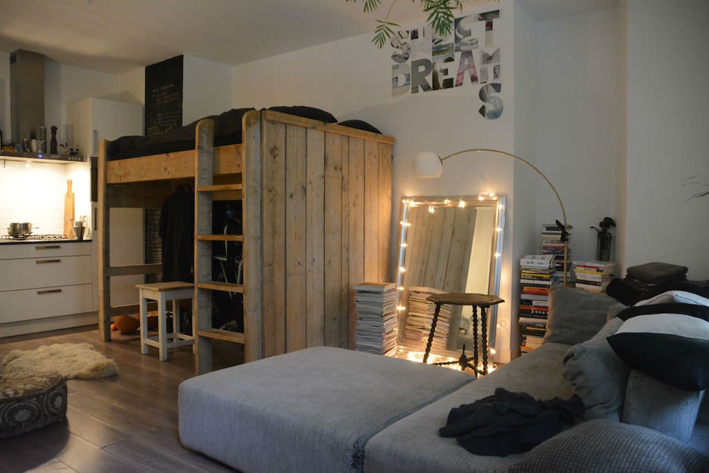 Shared 1 room studio house: the guest's sofa and the wooden loft bed where the hosts sleep