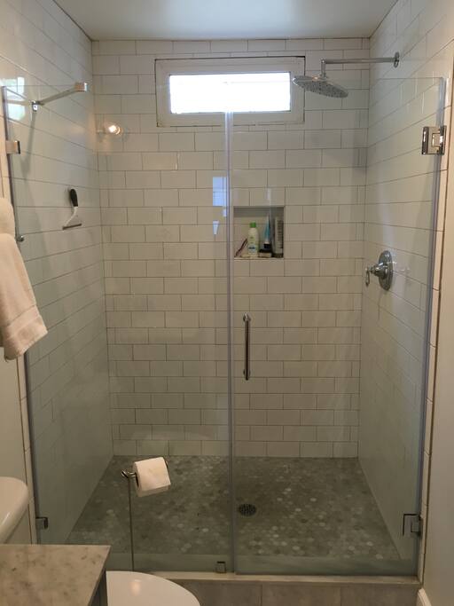 Large tiled shower. Swinging Glass Door. Extra Large Shower Head.