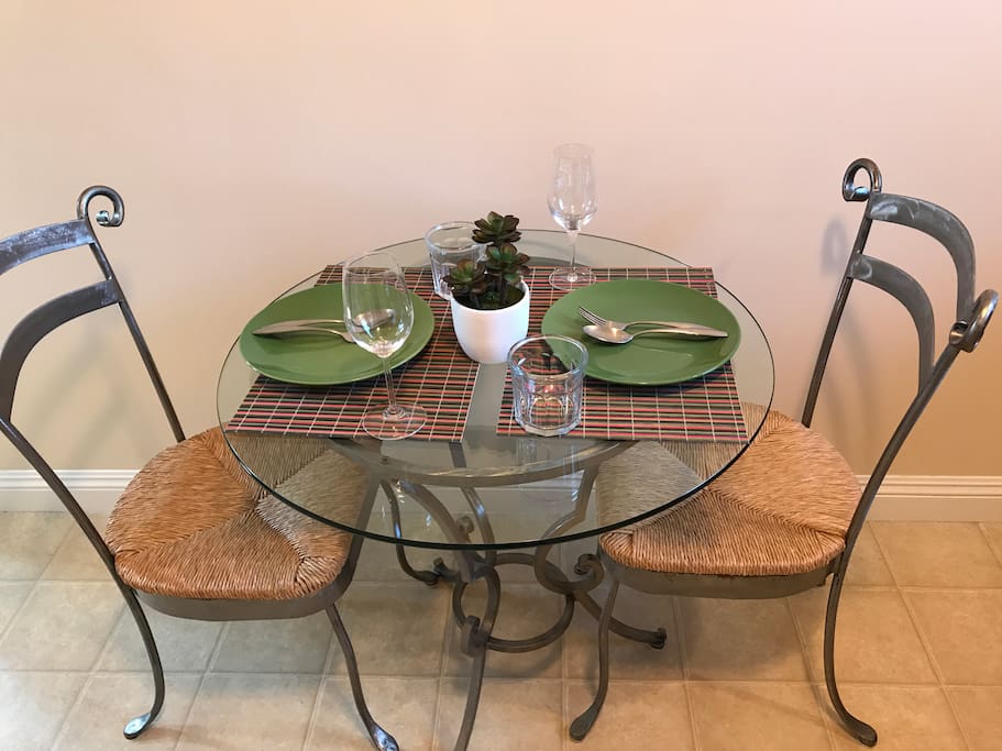Glass table with 2 chairs. Placemats, plates, utensils, wine glasses provided.