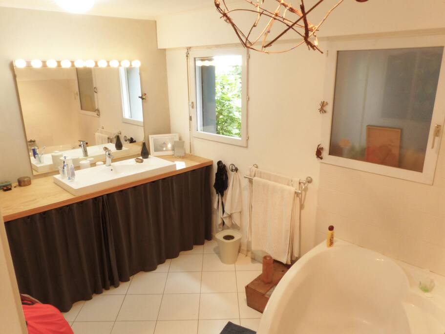 La salle de bain attenante, très claire, avec grande baignoire d'angle et fenêtre sur le jardin.