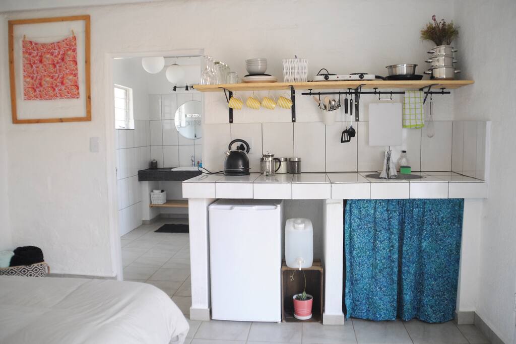 A small kitchen area comes with a mini fridge, tea kettle, hot plate, coffee, tea, sugar, and modest cooking utensils and dishes