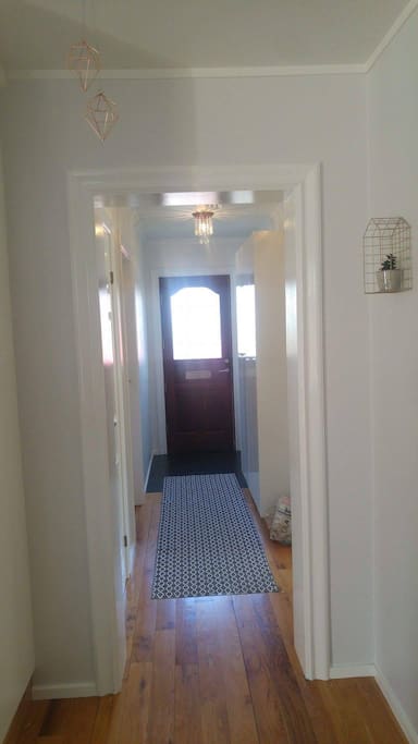 Hallway from front door, seen from kitchen leading to living room and smaller bedroom