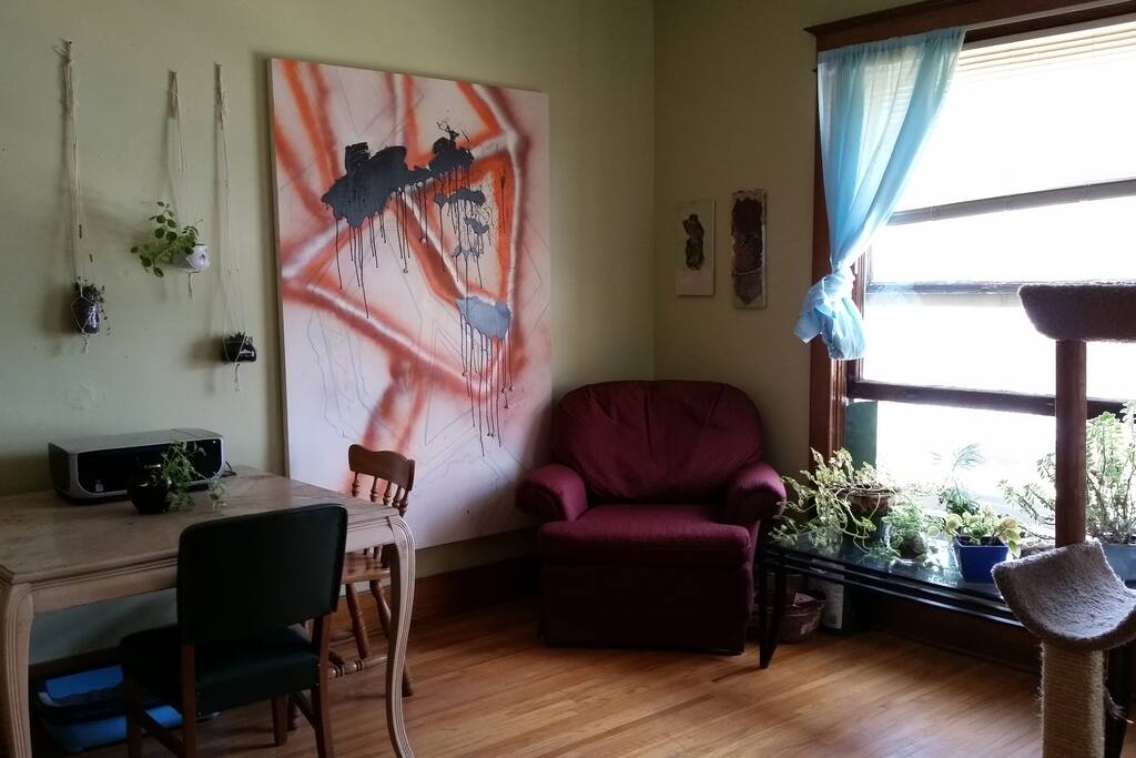 Many plants and paintings hanging in the space.
