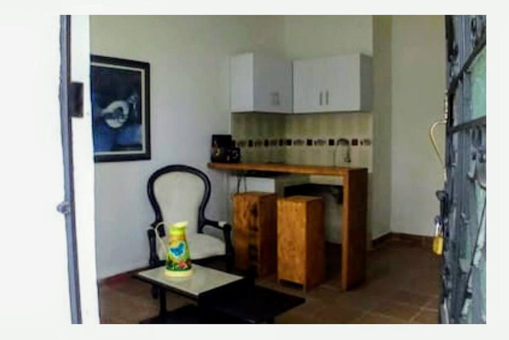 Entrada peatonal a salón comedor con cocineta y barra