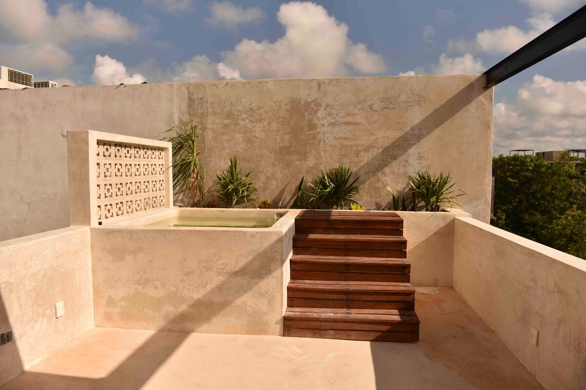 An outdoor terrace features a private plunge pool and steps leading up to the area. Surrounding greenery adds a natural touch to the space, complemented by a textured wall that enhances the atmosphere.