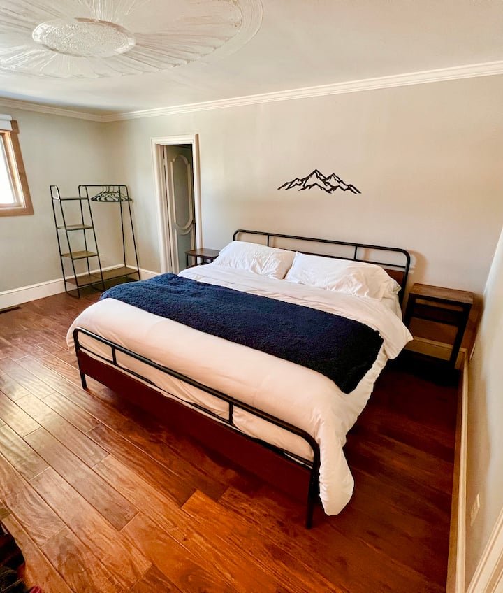 חדר שינה ראשי עם מיטת קינג סייז וחדר רחצה פרטי עם אמבטיה ומקלחת.