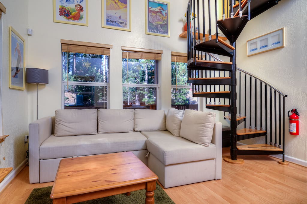 The open-concept living area has high ceilings, a comfy sectional couch and wood pallet fireplace.