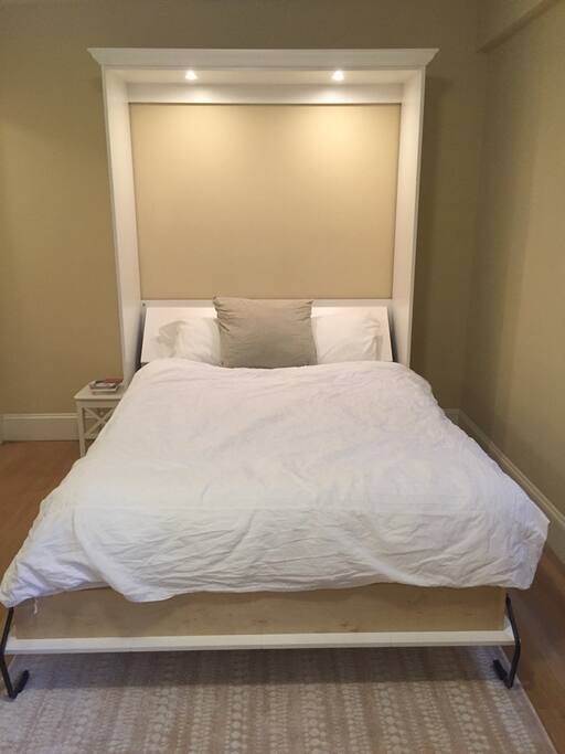Queen sized bed with reading lights that have a vintage metal on/off switch by the pillows.