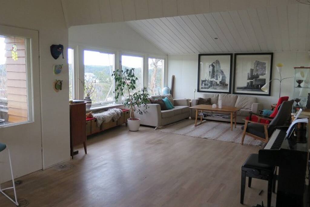 Åpen og lys stue med spisestue med langbord og doble dører ut til terrasse og hage.