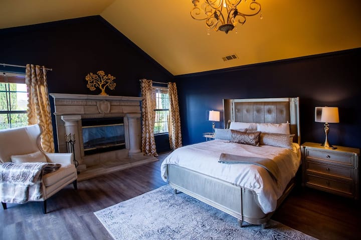Bedroom 1 is a luxurious dark blue accented by deep yellows and gold. High end linens and accents tie this space together. 