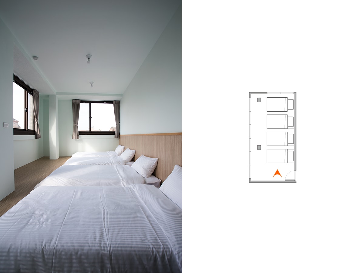 A bright room is furnished with three spacious beds dressed in crisp white linens. Natural light fills the space through large windows with simple curtains, enhancing the minimalist design of the pale green walls and wooden accents.