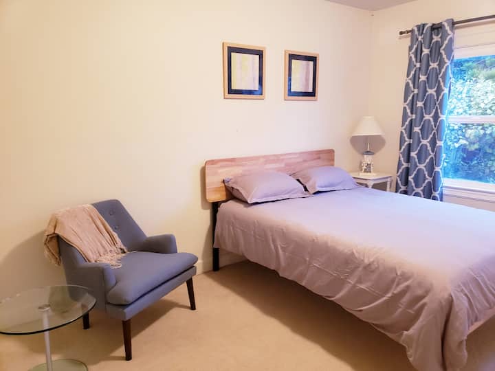 ห้องนอน #1 พร้อมเตียงควีนไซส์ที่สะดวกสบายเก้าอี้นวมที่วางกระเป๋าเดินทางและถังขยะของเล่นในตู้เสื้อผ้าสำหรับลูกน้อยของคุณ 