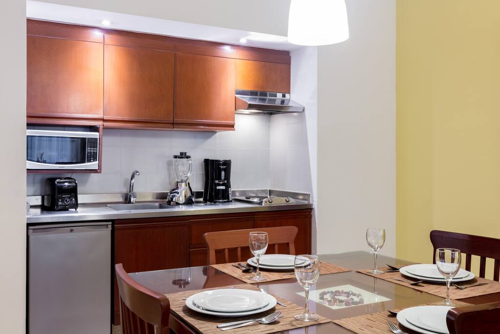 The kitchen has a blender, microwave, mini-fridge, stovetop, dishwasher, cookware, and dishes.