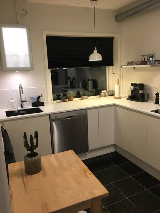 Køkken med opvaskemaskine, oven, køleskab samt fryser.