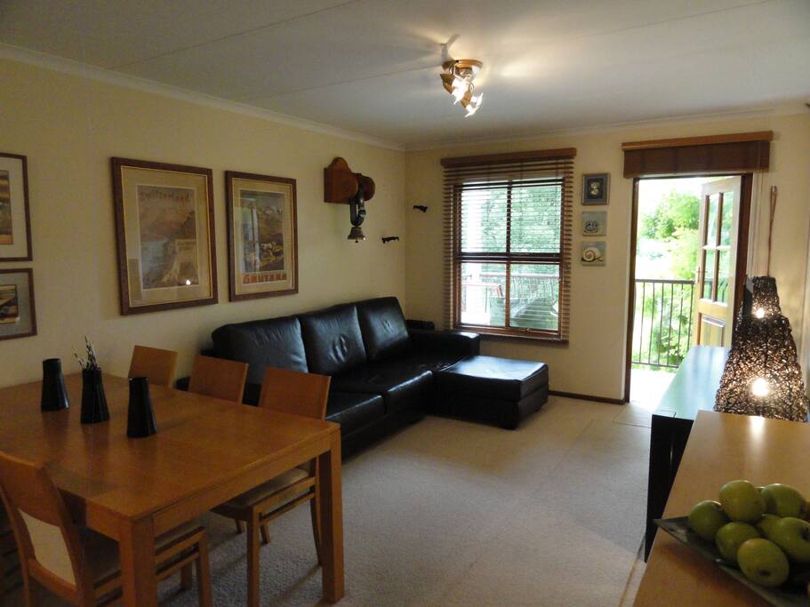 Dining table and lounge area leading out onto the balcony with a stunning view out onto a lawn.