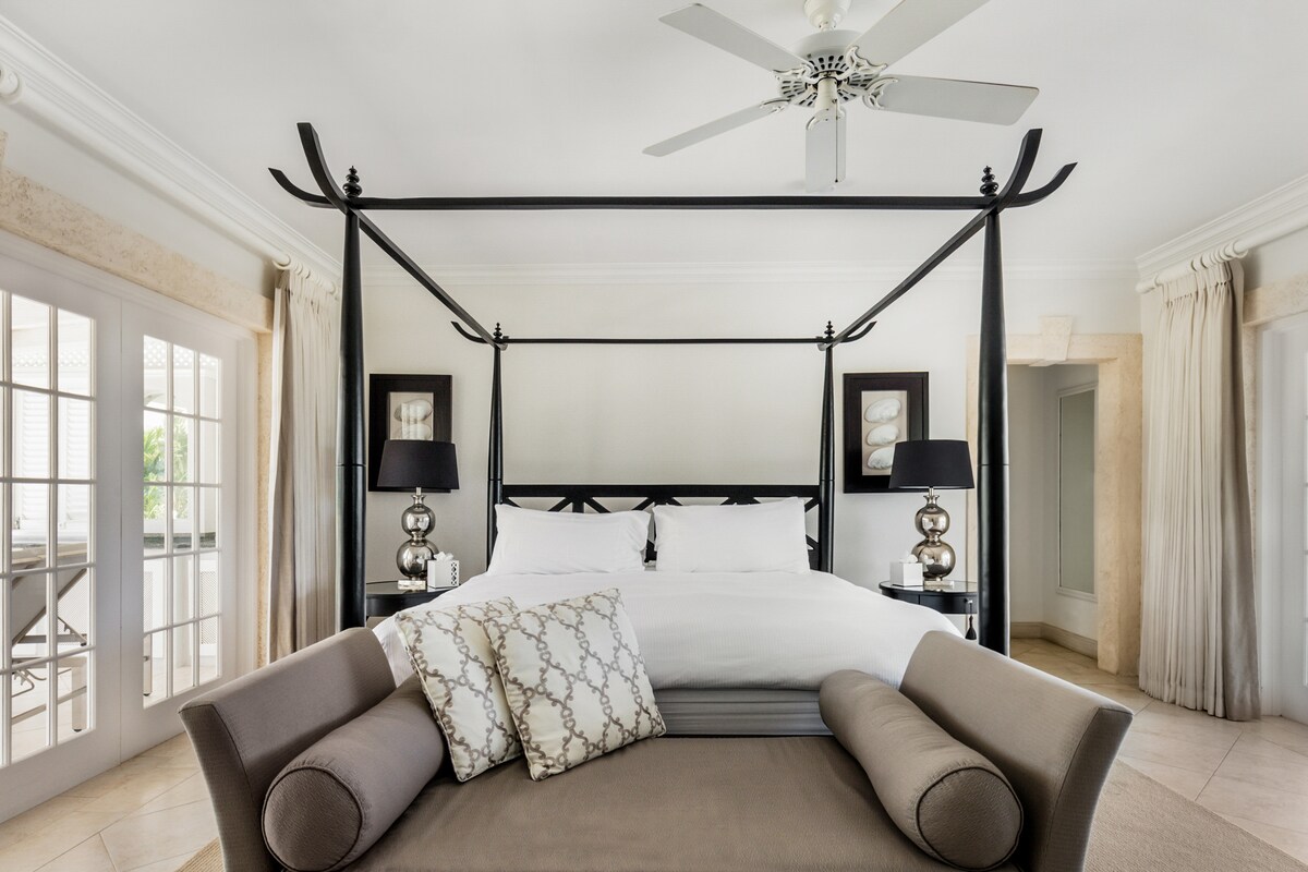 Un dormitorio principal bellamente diseñado con cama tamaño super king del Reino Unido, vistas a la piscina, aire acondicionado, ventilador de techo, caja fuerte, almacenamiento de ropa y un magnífico baño y ducha en la habitación.