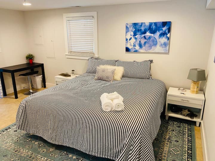 Recámara de la planta baja con una cama tamaño king, pisos de azulejo, mesitas de noche y muebles cómodos en una casa vacacional de 5 recámaras en Mount Pleasant, Carolina del Sur.