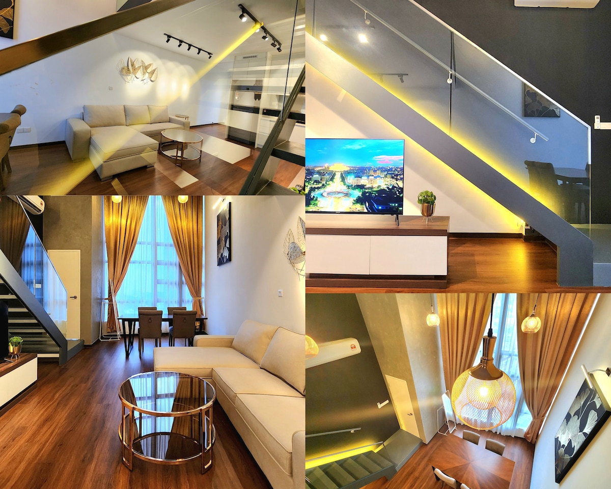 A modern living area is highlighted by a light-colored sectional sofa and a sleek glass coffee table. A large television is mounted on a white console, with decorative plants adding a touch of greenery. Soft lighting illuminates the space from above, complemented by floor-to-ceiling windows draped with elegant curtains.