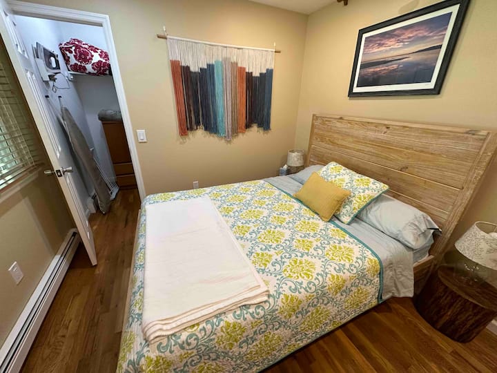 Dormitorio 3: "Seabird Nest" es acogedor con una cama tamaño queen con colchón firme,  moderno escritorio de pie con monitor de 27 pulgadas, libros para leer. Armario adjunto con plancha/ tabla de planchar y mantas adicionales, y mucho espacio para colgar o guardar tus artículos. 