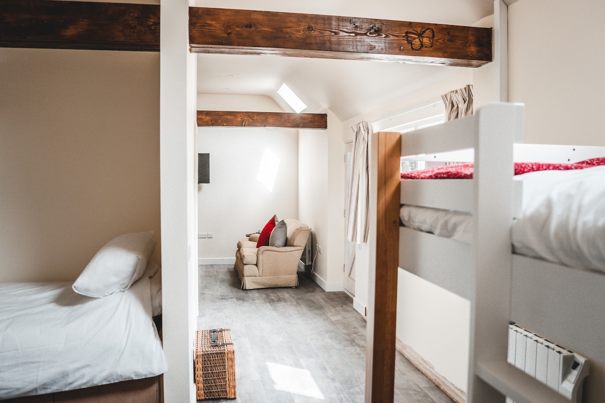 2 комплета кревети на спрат со големина за возрасни, како и дрвен кревет. Сите кревети се на едниот крај со каучите и телевизорот на другиот.