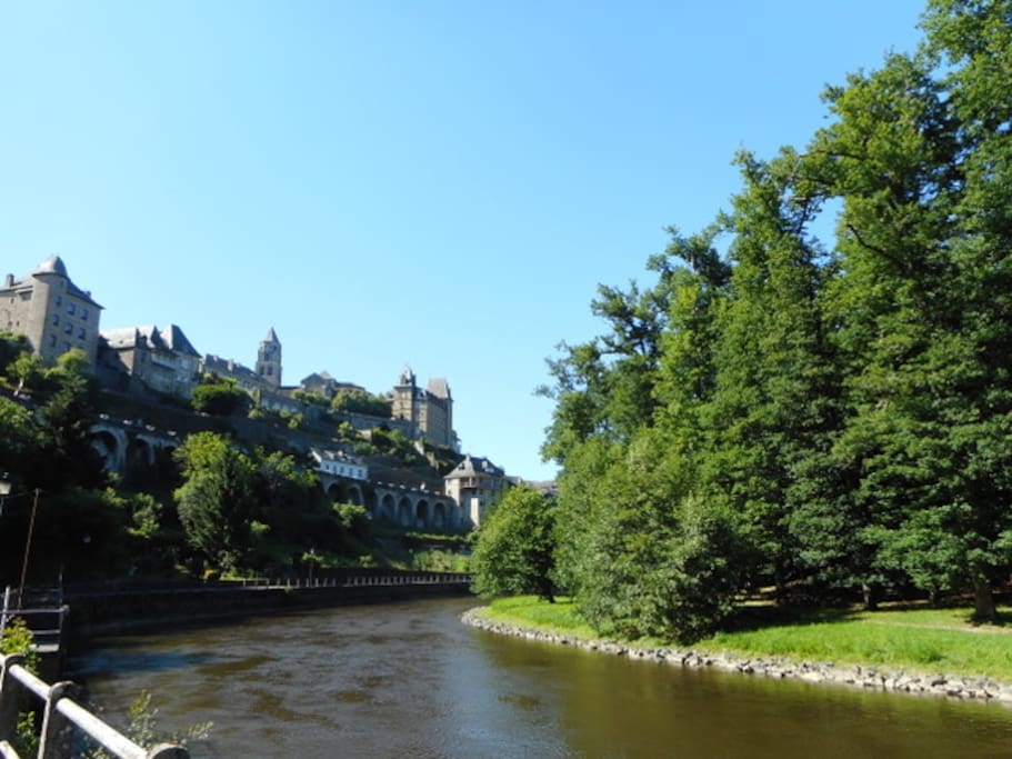 View of Uzerche Self-Catering apartments nestled between the turrets, as seen from the woodland walk by the River Vezere below.