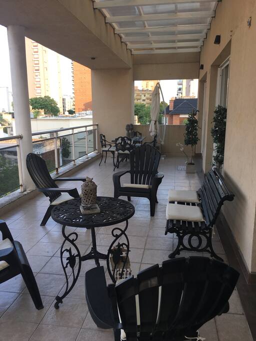 Balcón con mesa y sillas con acceso a cocina.