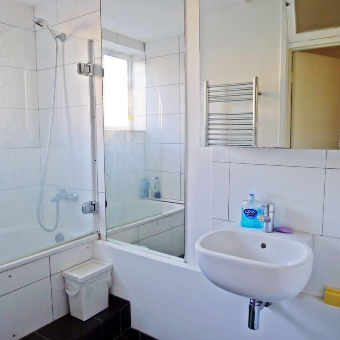A shared bathroom with a bath tub, a basin, and all toiletries