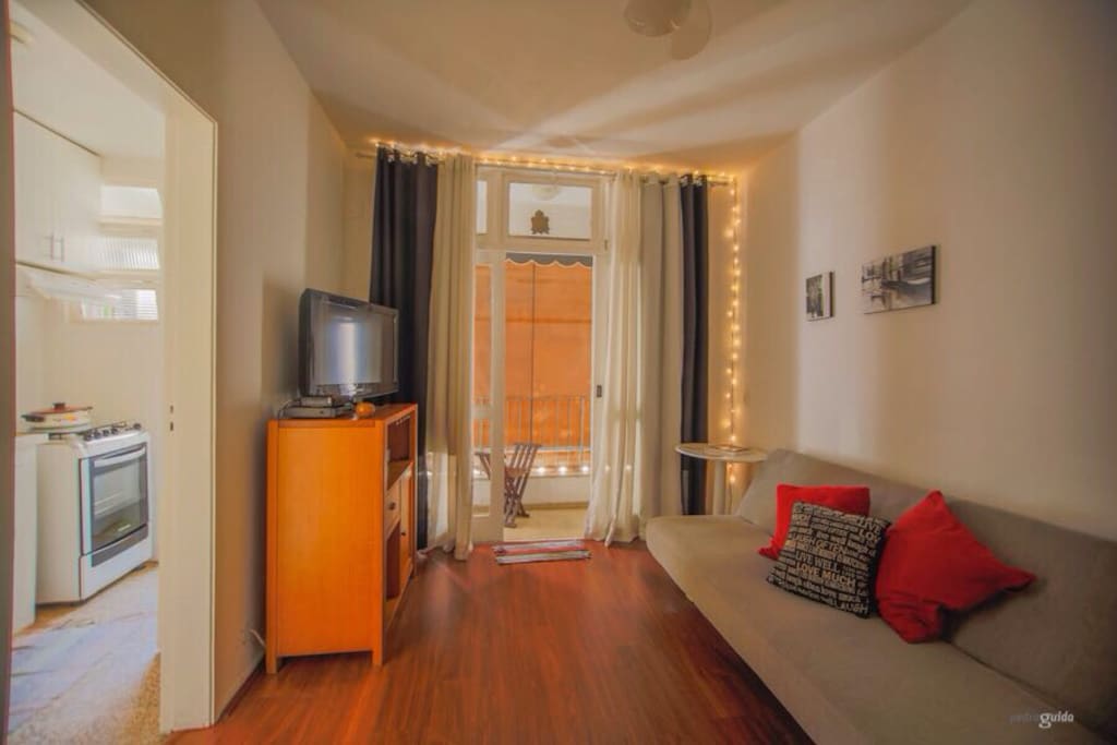 Sala com sofá-cama casal, TV, ventilador de teto e varanda