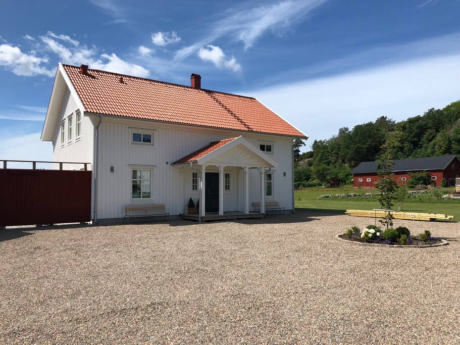 Husbild. Stor plats framför huset. Rondell med säsongens blommor. House picture.